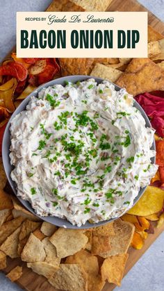 There is a grey bowl filled a light dip with bacon bits, chopped onions, Greek yogurt and other spices topped with chopped chives. The bowl is surrounded by an assortment of chips from pita chips to potato chips. Onion Dip Greek Yogurt, Bacon Onion Dip, Dip Greek Yogurt, Cold Dip, Nacho Fries, Giada Recipes, Vegetable Chips, Spicy Appetizers, Dipping Oil