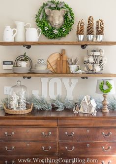 a wooden dresser topped with lots of shelves filled with christmas decorations and wreaths on top of it