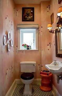 a bathroom with a toilet, sink and mirror on the wall next to each other