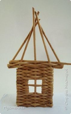 a small house made out of wicker on a white tablecloth with a wooden stick sticking out of it's roof