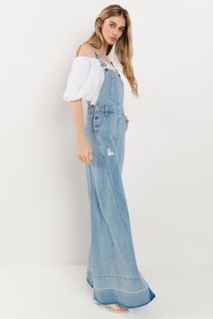 Choose comfort and style with the Women's Distressed Wide Leg Denim Overall. The adjustable straps, kangaroo chest pocket, and front and back pockets provide convenience, while the wide western legs, side buttons, and distressed accents add a trendy touch. Stay on trend in these comfortable, boho-inspired overalls. 34" INSEAM SLEEVELESSBUCKLE CLOSUREADJUSTABLE STRAPSKANGAROO CHEST POCKETFRONT/BACK POCKETSWIDE LEG Dark Wash Denim Jumpsuit With Adjustable Straps, Casual Jeans With Suspenders In Medium Wash, Casual Denim Blue Jeans With Suspenders, Casual Cotton Jeans With Suspenders, Medium Wash Wide-leg Overalls With Pockets, Light Wash Overalls With Pockets For Fall, Fall Light Wash Overalls With Pockets, Spring Jeans With Adjustable Straps, Casual Wide Leg Bottoms With Adjustable Straps