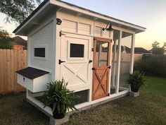 a white chicken coop sitting on top of a lush green field