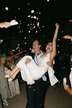 a man carrying a woman on his back as confetti falls in the air