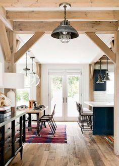 an open kitchen and dining room with wooden beams on the ceiling, white walls and blue cabinets