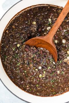 a wooden spoon in a pot filled with beans and other things to make it look like they are cooking