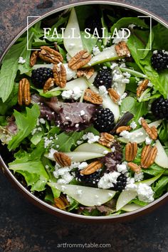 a salad with apples, blackberries and pecans in it