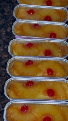 four plastic containers filled with pineapple and cherries on top of a countertop