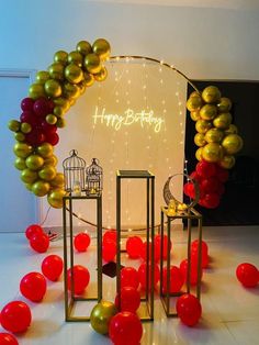 a birthday arch with balloons and lights in the shape of a birdcage on it