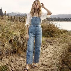 Experience effortless style and comfort with the Combinaison Angela. This high-waisted, classic straight wash jumpsuit by Doen offers a flattering fit and timeless design. Made with quality materials, it's perfect for any occasion while adding a touch of elegance to your wardrobe. Overalls Outfit Cottagecore, Styling Jean Overalls, How To Style Jean Overalls, Summer Overalls Outfit, Homestead Attire, Women’s Overalls Outfit, Cotton Overalls Outfit, Overalls Outfit Women, Overalls Outfit Vintage