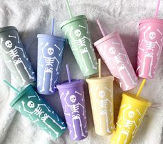 six different colored cups with skeleton designs on them and straws in each cup,