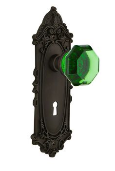 a green door handle on an old fashioned black wall mounted cabinet with ornate carvings and scrolls