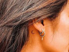 a close up of a woman's ear with two small hoops on it