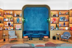 a living room filled with furniture and bookshelves covered in wooden shelves next to a blue wall