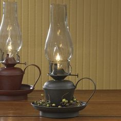 two glass teapots with lights on top of them sitting on a wooden table