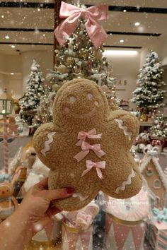 a person holding up a teddy bear in front of christmas trees