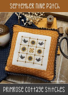 a cross stitch pillow sitting on top of a wooden table