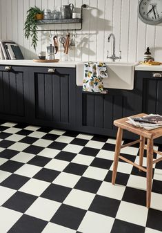 a black and white checkered floor in a kitchen with a clock on the wall