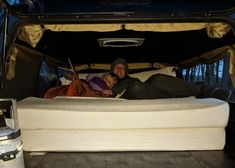 a man and woman laying in the back of a truck