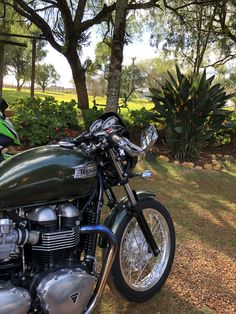 a green motorcycle parked on top of a grass covered field