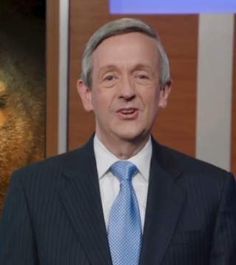 a man wearing a suit and tie standing in front of a painting