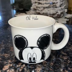 a mickey mouse coffee mug with the word oh hello on it's side sitting on a granite countertop