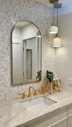 a bathroom with marble counter tops and gold faucets on the sink, along with an arched mirror