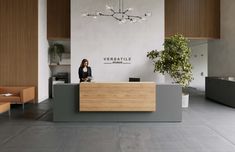 a woman is sitting at the front desk of a reception area in a modern office