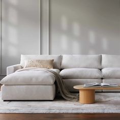 a white couch sitting on top of a wooden floor next to a table and chair