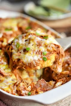 a close up of a spoon full of food with meat and cheese on it in a casserole dish