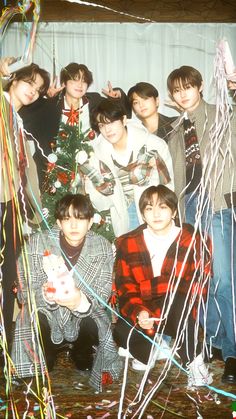 a group of young men standing next to each other in front of a christmas tree