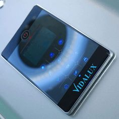 a cell phone sitting on top of a white table next to a blue and black clock