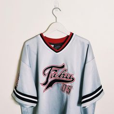 Vintage y2k silver / white / black Fubu jersey. FUBU 05 Jersey. FUBU 05 graphic logo on chest and back. embroidered badges on sleeve and chest. FUBU ATHLETICS 1992  Fubu jersey Fubu top Fubu shirt Fubu t shirt P2P 28 INCH, LENGTH 34 INCH Size XXL Good condition  UK AND WORLDWIDE SHIPPING SERVICE  FULLY TRACKABLE SHIPPING SERVICE Sporty Tops With Embroidered Logo For Streetwear, Sporty Streetwear Top With Embroidered Logo, Team-colored Letter Print Jersey For Streetwear, Sporty Embroidered Graphics Tops For College, Sporty Tops With Embroidered Graphics For College, Sporty College Tops With Embroidered Graphics, Throwback College Tops With Embroidered Logo, Team-colored Graphic Print Jersey For Streetwear, Collegiate Letter Print Jersey For Streetwear