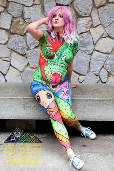 a woman with pink hair sitting on a stone bench wearing colorful leggings and a t - shirt