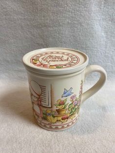 a cup with a lid on it sitting on top of a white tablecloth covered floor