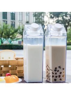 two containers filled with milk sitting on top of a table