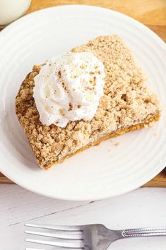 a piece of pie on a white plate with a fork and glass of milk next to it