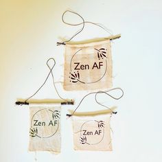 two small bags hanging from strings on a white wall with the words zen af and zen af printed on them