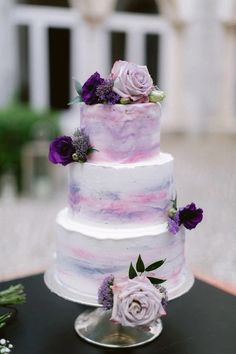 a three tiered cake with purple flowers on top