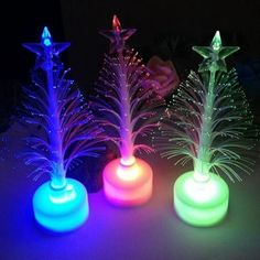 three lighted trees in different colors on a table