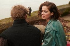 a woman standing next to a man on top of a hill