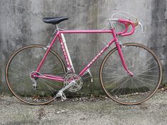 a pink bike leaning against a concrete wall