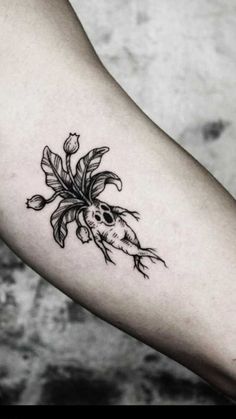 a woman's arm with a flower and skull tattoo on the left inner forearm