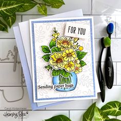 a card with flowers in a vase and a toothbrush next to it