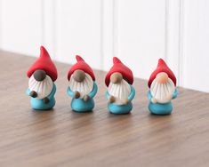 four little gnome figurines sitting on top of a wooden table