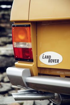 the bumper sticker on the back of a yellow land rover