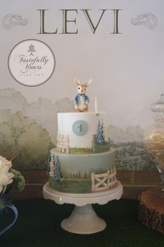 a three tiered cake with an animal on top is displayed in front of a backdrop