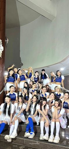 a group of young women posing for a photo on steps with their arms in the air