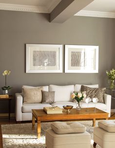 a living room with couches, tables and pictures hanging on the wall above them