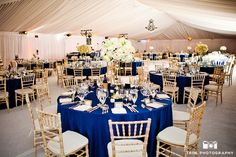 the tables are set up with blue linens and white flowers in centerpieces