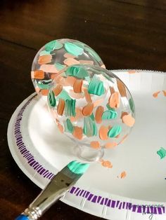 a paper plate with confetti on it next to a knife